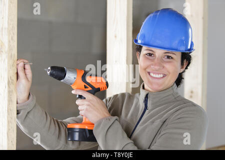 Frau builder Bohren an der Wand Stockfoto