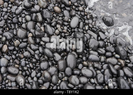 Glatte nasse Steine mit Wasser in der Ecke. Bei Djúpalónssandur Strand genommen, Island. Stockfoto