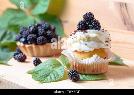 Blackberry Kuchen mit Beeren und Sahne auf einem Holztisch. Fokus auf den Vordergrund. Stockfoto