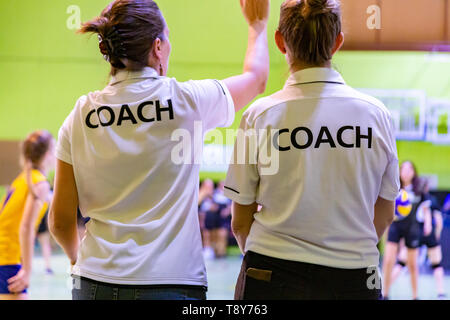 Weibliche Trainer in Weiß TRAINER T-Shirt an einem Indoor sport spiel Stockfoto