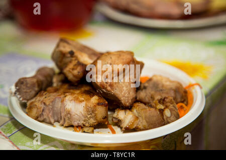 Stücke von gebratenem Fleisch auf den Kohlen liegen auf dem festlichen Tisch. Stockfoto