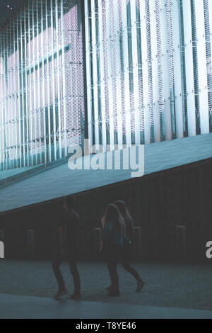 Gruppe von Menschen zu Fuß in das Zentrum der Stadt bei Nacht. Bau hinter Ihnen mit Hintergrundbeleuchtung Stockfoto