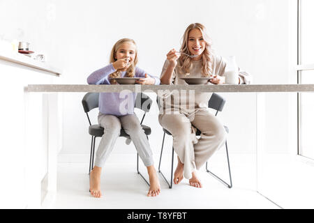 Bild von zwei glückliche Mädchen Schwestern in Küche drinnen essen, ein Frühstück zusammen haben. Stockfoto