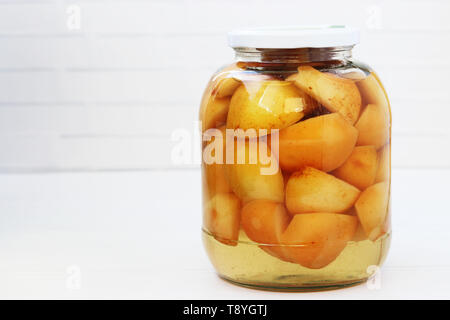 Eingemachte Äpfel in Sirup in einem Glas auf einem weißen Hintergrund, Platz für eine Inschrift