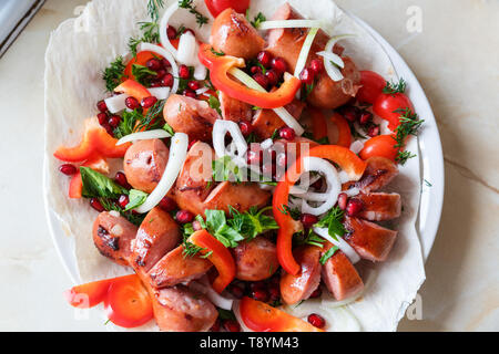 Gebratene Würstchen mit Gemüse auf einem dünnen, flachen Kuchen in einer Platte. Stockfoto