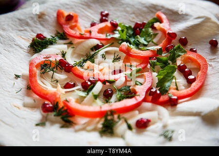 Gemüse auf eine dünne Kuchen in einer Platte. Paprika, Zwiebeln, Granatapfel, Tortilla für gebratenes Fleisch Stockfoto