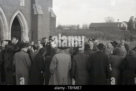 1950, historische, eine Gruppe von Hochzeitsgästen tragen Hüte und Pelzmäntel außerhalb der Kirche bereit, ein vor kurzem verheiratetes Paar willkommen, England, UK. Stockfoto