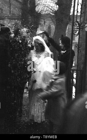 1950, historische, eine frisch verheiratete Ehepaar mit Konfetti an den Toren geduscht zu der Kirche, England, UK. Stockfoto