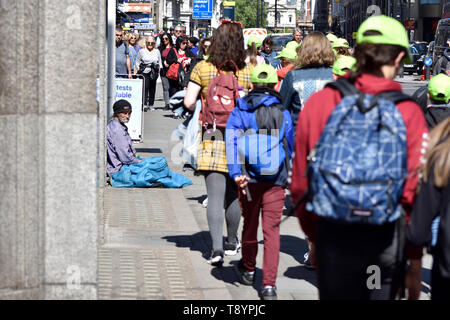 London, England, UK. Obdachlosen Mann auf der Straße mit einer Gruppe von Schülern vorbei gehen - der Strand Stockfoto