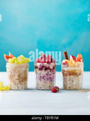 Sortiment über Nacht Hafer, Bircher Müsli mit frischen Beeren und Früchte in einem Glas Gläser auf Holztisch. Kopieren Sie Platz. Stockfoto