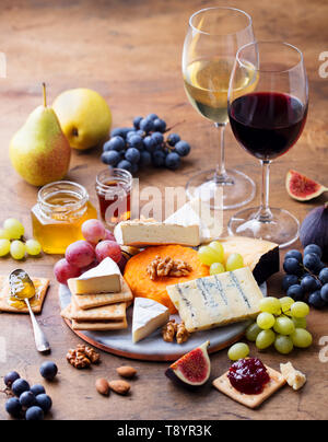 Trauben, Käse, Feigen und Honig mit einem Gläschen Rot- und Weißwein auf einer hölzernen Hintergrund. Stockfoto