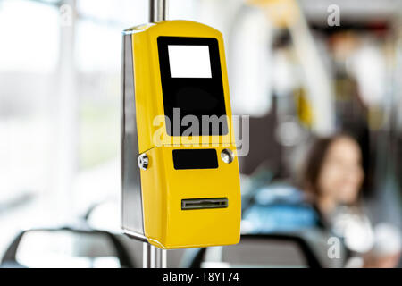 Gelbe Fahrkartenautomaten in der modernen Tram mit weiblichen Passagier auf dem Hintergrund Stockfoto