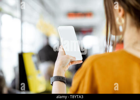 Frau mit Telefon mit leeren Bildschirm Paste zu kopieren, während in der Straßenbahn stehend Stockfoto