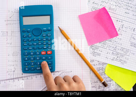 Wissenschaftlicher Taschenrechner in den Händen Während mathematische Übung. Schule Konzept. Stockfoto