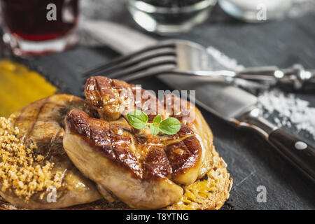 Gebratene Gänsestopfleber mit Mango Püree auf dunklem Hintergrund. Gänseleber. Stockfoto