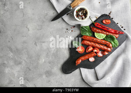 Schiefer mit köstlichen gegrillten Würstchen und Gemüse auf Tisch Stockfoto