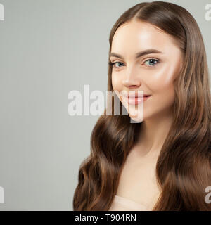 Attraktive Frau mit klaren Haut und gesunde lockige braune Haare lächelnd. Schönes Gesicht. Hautpflege und Haarpflege Konzept Stockfoto