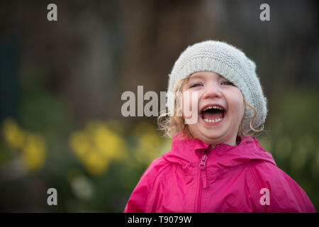 Kleines Mädchen im Frühling Garten lachend mit Hut Stockfoto