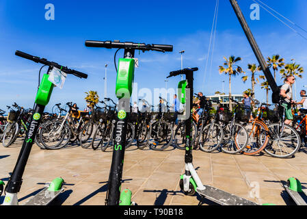 Valencia, Spanien - 12. Mai 2019: Fahrräder zum Mieten für Touristen und Elektroroller von Kalk an den Strand von Valencia geparkt. Stockfoto