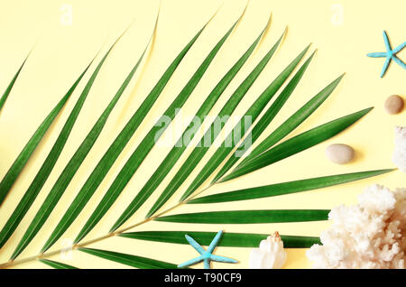 Sommer vibes. Tropische palm leaf, Muscheln und Seesterne. Flach, Ansicht von oben. Gelber Hintergrund Stockfoto