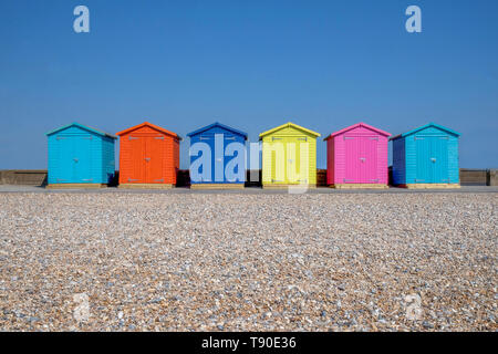 Eine Linie der sechs bunten Badekabinen, jeder hat eine andere Farbe im Vordergrund ist ein Kieselstrand und hinter ist ein strahlend blauen Himmel, Seafor Stockfoto