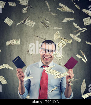 Staatsbürgerschaft für Investitionen Konzept. Happy Geschäftsmann mit zwei Pässen unter Geld Regen Stockfoto