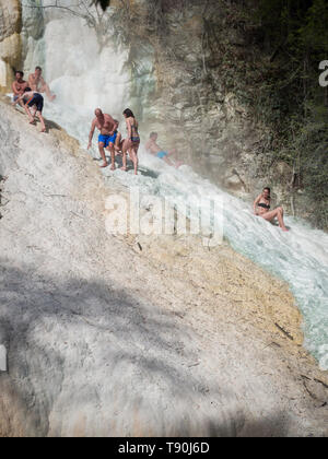 Bagni San Filippo, Italien - 24 April 2019: Menschen Ruhe auf den thermischen Salz Wasserfälle der Mineralquellen von Bagni San Filippo an einem sonnigen Tag. Stockfoto