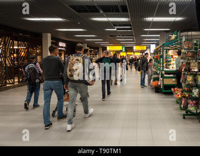 Fluggäste gehen zwischen den Geschäften und Restaurants in einer der wichtigsten councourses der Flughafen Schiphol, Amsterdam Stockfoto