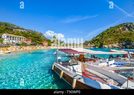 Touristen, die sich in der klaren, blauen und türkisfarbenen Wasser und am Sandstrand von Palaiokastritsa entfernt an der ägäischen Insel Korfu, Griechenland. Stockfoto