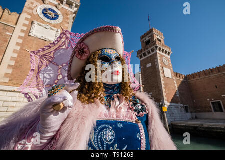 Porträt einer Feminine maskierte Person in einem schönen kreativen Kostüm, in den Gebäuden der Arsenale posiert, feiert die Venezianischen Karneval Stockfoto