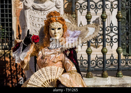 Porträt einer Feminine maskierte Person in einem schönen kreativen Kostüm, in den Gebäuden der Arsenale posiert, feiert die Venezianischen Karneval Stockfoto