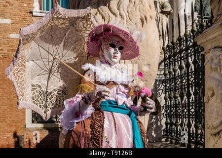 Porträt einer Feminine maskierte Person in einem schönen kreativen Kostüm, in den Gebäuden der Arsenale posiert, feiert die Venezianischen Karneval Stockfoto