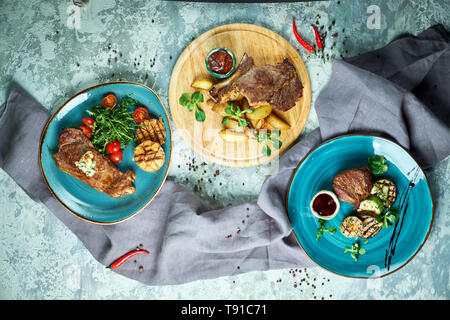 Sortierte lecker Gegrilltes Fleisch mit Gemüse Grau strukturierten Hintergrund. Schöne Servieren von Speisen. Ansicht von oben Stockfoto