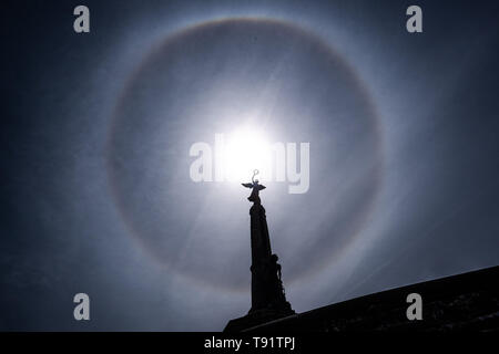 Aberystwyth Wales UK, Donnerstag, den 16. Mai 2019 Deutschland Wetter: eine perfekte Runde sun Halo, gebildet, wie die Strahlen der Sonne durch Eiskristalle in der oberen Atmosphäre, am Himmel über der Silhouette des War Memorial Aberystwyth. Die Halos, immer auf 22º von der Sonne, häufig darauf hin, dass Regen wird innerhalb der nächsten 24 Stunden fallen, da die cirrostratus Wolken, die sie verursachen, kann ein sich näherndes Frontschutzsystem bedeuten. Das Wetter wird eingestellt über Nacht aus dem feinen warmen Bedingungen zum kühler und feuchter Tage, eher typisch für Mitte Mai. Photo credit Keith Morris/Alamy Leben Nachrichten zu ändern. Stockfoto