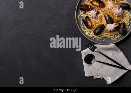 Mediterran Pasta mit Tintenfisch, Muscheln und Tomaten souse in der Platte. Freier Platz Ecke für Text, Hintergrund für Banner Stockfoto