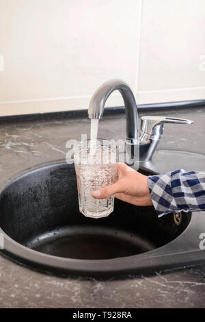 Frau Füllung Glas mit Wasser aus einem Wasserhahn Stockfoto