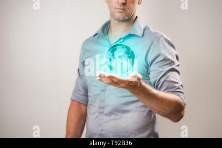 Casualy gekleidete Geschäftsmann Holding virtuelle Projektion der Welt in seiner Hand. Stockfoto