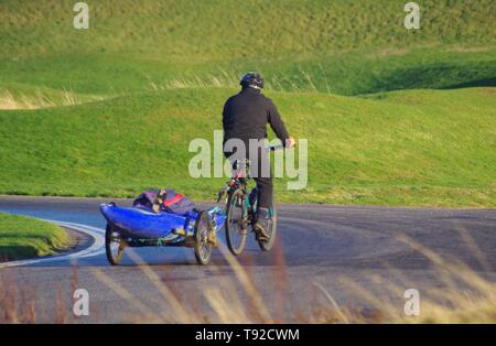 Mann Toeing einen blauen Kajak mit dem Fahrrad nach Aberdeen Strand an einem sonnigen Wintertag. Schottland, Großbritannien. Stockfoto