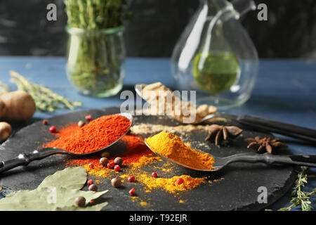 Löffel mit verschiedenen Gewürzen auf schiefer Platte Stockfoto