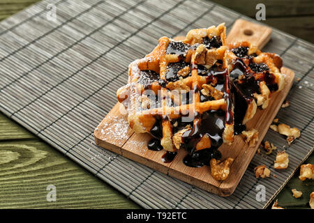 Leckere Waffeln mit Schokolade und Nüssen auf Holzbrett Stockfoto
