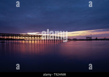 Lange Belichtung eines Pier vor einem wunderschönen Sonnenaufgang am Neuse River Estuary in einem Park in Minnesott Beach, North Carolina. Stockfoto