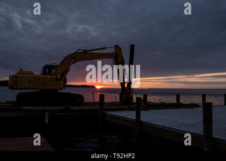 Eine Ramme ruht auf einer schwimmenden Plattform von einem Pier nach verwendet werden, um Schäden vom Hurrikan Florence wiederherstellen. Sonnenaufgang im Hintergrund. Stockfoto