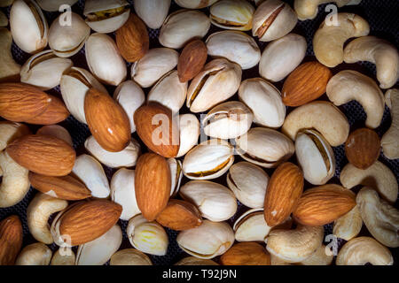 Mandeln, Pistazien, Cashewkerne zusammen auf schwarzem Hintergrund gemischt, es ist gesunder Mix. Stockfoto