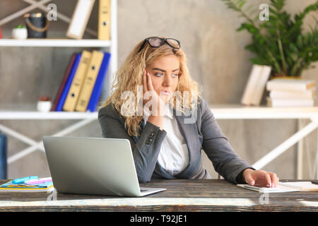 Langweilig junge geschäftsfrau am Tisch im Büro Stockfoto