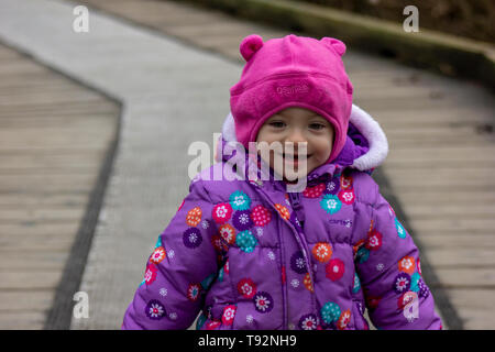 20 Monate altes Baby genießt das schöne Wetter. Für die kalten gebündelt. 1,5 Jahre altes Kleinkind wandern in Parks, wenn die Sonne scheint. Stockfoto