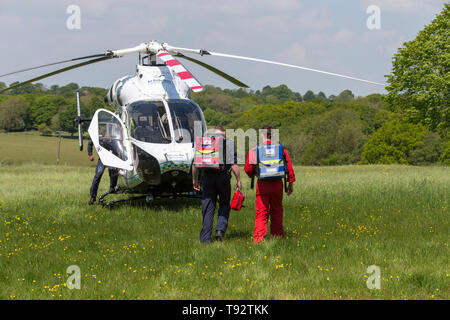 Air Ambulance Crew gehen Sie in Richtung einer Kent, Surrey Sussex MD 902 Explorer Hubschrauber nach einem Callout in Tenterden, Kent, Großbritannien Stockfoto