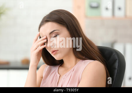 Frau leidet unter Kopfschmerzen im Büro Stockfoto