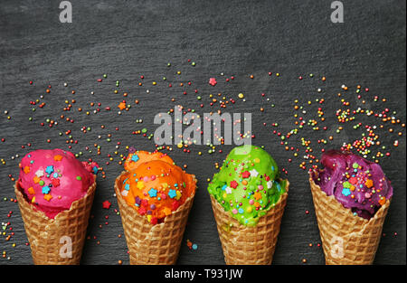 Waffeln mit Eis und leckere Farbe besprüht auf dunklem Hintergrund Stockfoto