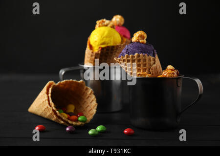 Waffeln mit köstlichen Farbe Eis in Metall Tassen auf hölzernen Tisch Stockfoto