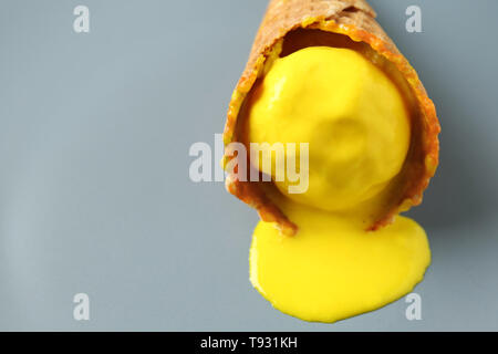 Waffel Kegel mit köstlichen geschmolzene Eis auf grauem Hintergrund Stockfoto